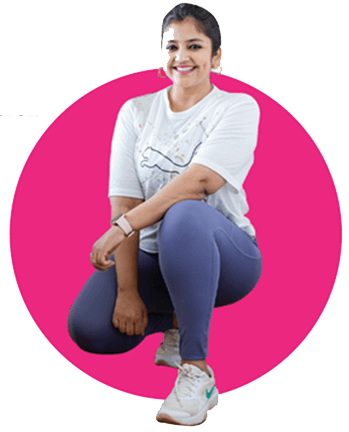 A woman wearing pink leggings sitting on on her ankle and smiling